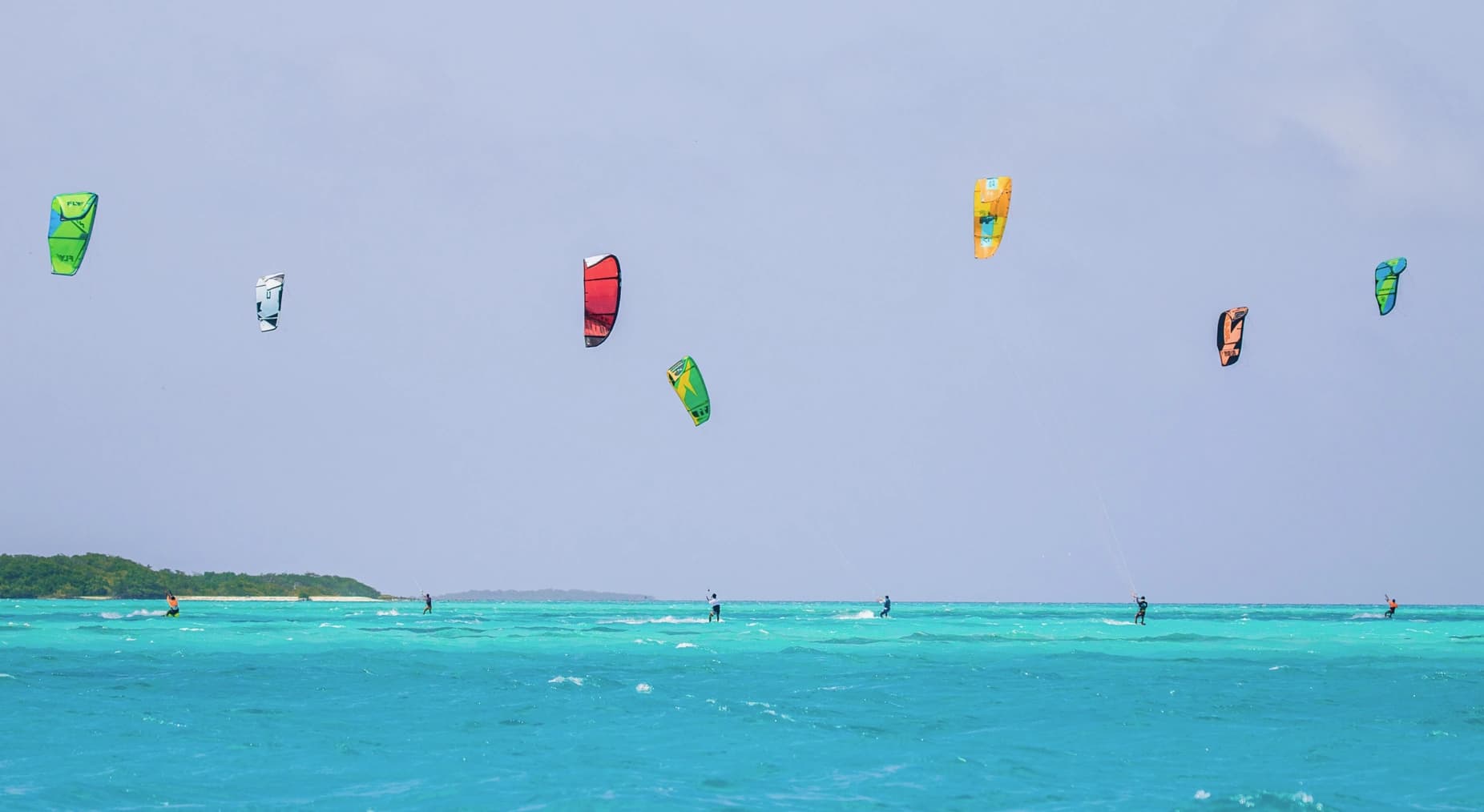 Des ailes de kite colorées au-dessus d’un lagon.