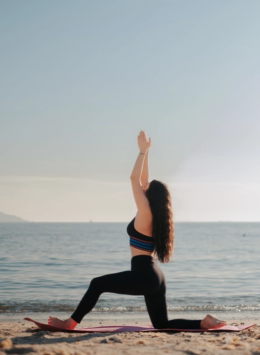 Une posture de yoga sur la plage, les bras tendus vers le ciel.